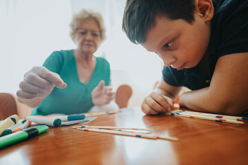 A young boy enjoys a game of pick-up sticks with his grandmother in a warm and cozy living room...