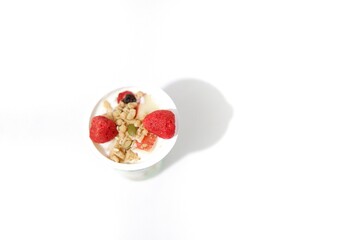 In selective focus yogurt with mixed dried fruit on top,top view with copy space and white isolated background 