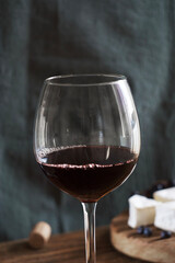 A glass of red wine stands on a wooden table
