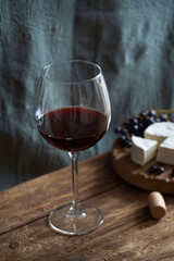 A glass of red wine stands on a wooden table