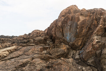 View of dark sea rocks against the ocean and cloudy sky. Preserved nature.