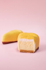 Slice of cheesecake cut in half covered with yellow chocolate velour on pink background with copy space. 
