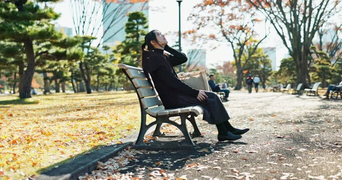 Asian woman, walking and relax on park bench with phone for social media, communication or networking. Female person sitting with mobile smartphone for online search, streaming or break in nature