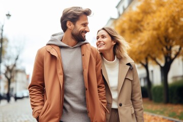 Fototapeta premium A couple strolls happily through a vibrant autumn landscape, surrounded by colorful trees and fallen leaves. Laughter and warmth fill the air as they share a moment together