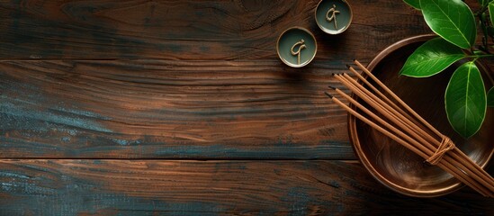 Fototapeta premium Flat lay arrangement featuring incense sticks on a wooden table with space for text Om ligature. Copy space image. Place for adding text and design