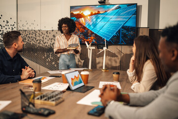 Interracial businesswoman presenting solar panels to diverse investors