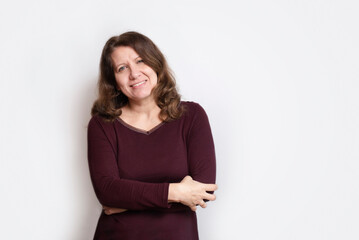 Fototapeta premium A smug middle-aged woman hugs herself and smiles, she is happy that she got rid of depression and panic attacks in life. Regular physical exercises helped the woman get rid of depression