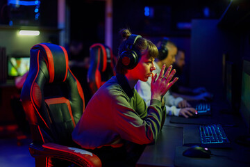 Tense gamer girl sitting in game room in uptight situation in game. © Zamrznuti tonovi