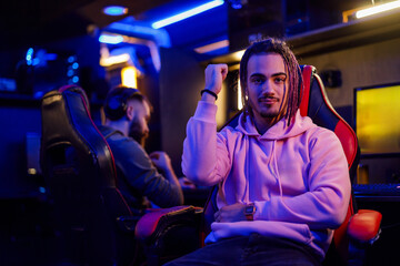 Gamer with dreadlocks is sitting in cybercafe and celebrating victory.