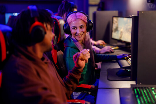 Multicultural gaming buddies with headset giving bro fist at cybercafe