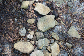 Diverse array of grey stones and pebbles covering the ground during daytime. Top view on different sized rock fragments lying on soil. Soil erosion concept. 
