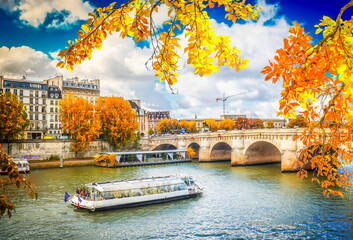 Pont Neuf and river Seine waters with cruise ship, blue sky with clouds, Paris at autumn, France,