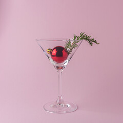 Christmas tree bauble in martini glass on pastel pink background. Minimal Christmas or New Year concept.