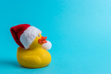 Rubber duck with Santa hat on blue background. Minimal Christmas or New Year concept.