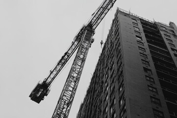 Fototapeta premium Construction crane overseeing high rise building development at a bustling construction site