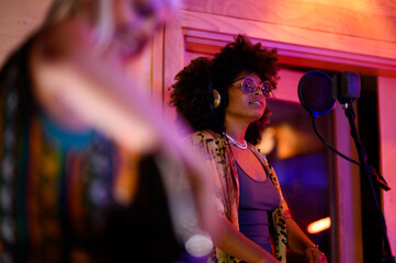 Portrait of latino female singing song on microphone in a music studio