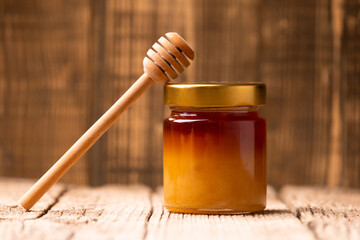 Buckwheat honey and honey spoon on wooden background