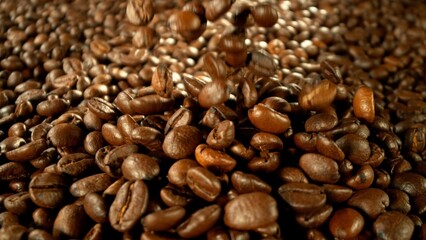 Roasted coffee beans falling on heap.
