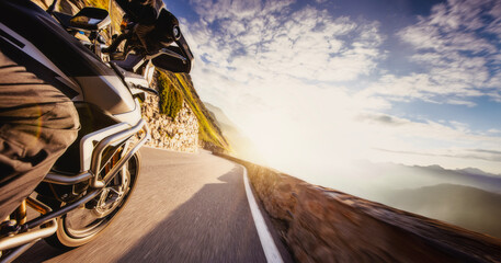 Motorbiker riding in Alps, dramatic sky. Travel and freedom, outdoor activities