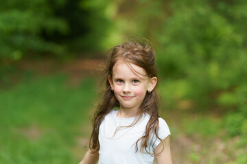 Little beautiful girl on the background of the road in the park. Happy childhood concept outdoors