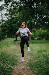 A cheerful young woman jumps with energy in a vibrant green park. The image captures a sense of freedom and joy in nature.