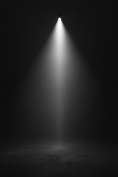 A single spotlight shines in a dark room, creating a dramatic and focused illumination that highlights the texture of the floor