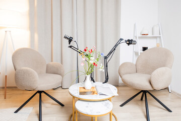 Two stylish armchairs and a decorative table set in a cozy living room with flowers and natural...
