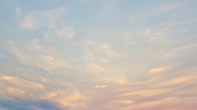 Beautiful wavy clouds in pastel colors of pink, yellow and blue fill a vast sky, creating a natural abstract background image of serenity and peace