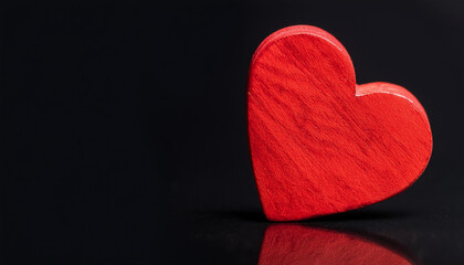 Red wooden heart shape isolated on black backdrop. Love, romantic, and Valentine's day concept.