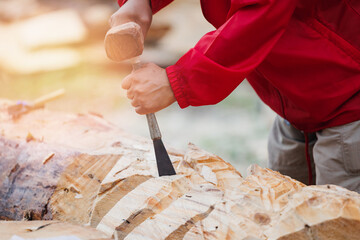 Lumberjack uses mallet and chisel to create beautiful wood carvings.