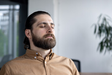 Professional man practicing meditation in office. Embodying relaxation and mindfulness, he takes a...