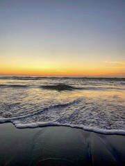 Orange and yellow sunset on beaches of  San Diego California, waves crashing on sand