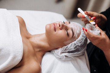 Side view portrait of young relaxed woman on procedure for improvements skin. Concept of special masks and creams for moisturizing. Self care spa concept. Advertising of cosmetology, cleanliness.