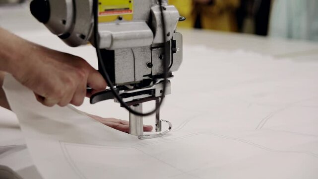 A man makes clothing patterns with a cutter knife in a factory. Cutting room, cutting cloth tailoring knife.
