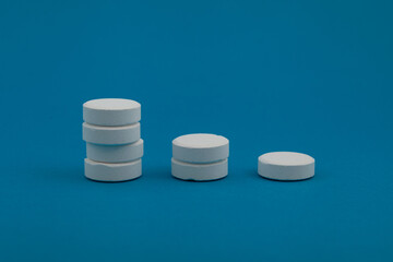 Round white Chlorine tablets on blue background. Bar graph, Chart down, pills. Reducing the use of chlorine-containing compounds and other hazardous chemicals