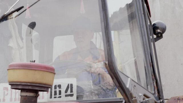 A worker is securely operating heavy machinery from a cabin at a construction site