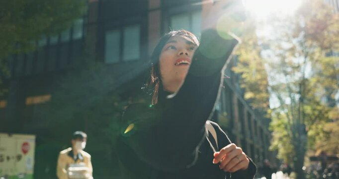 Asian, woman and smartphone in city, photography and travel with lens flare on commute. Cityscape, filming or taking picture of journey in Tokyo or urban street, tech and sunshine with adventure
