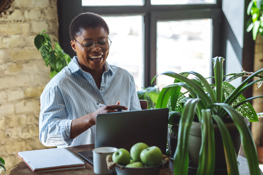 Cheerful healthy African American woman with laptop at home or in modern green office. Concept of video call, freelance job, studying remotely, learning, teaching languages, international education