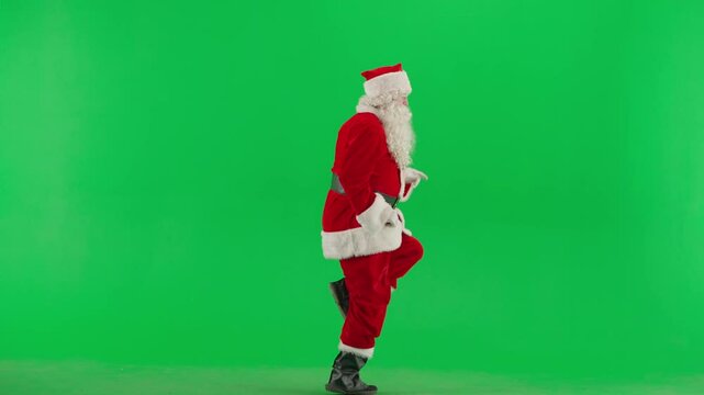 Portrait of man dressed as Santa on chroma key green screen background. Santa Claus in red outfit dancing trend shuffle dance jumping in place.