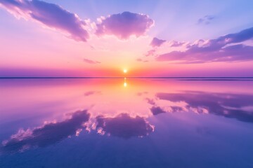 Fototapeta premium A serene view of mirror-like salt flats reflecting a vibrant sunrise with soft pink and purple hues and scattered clouds in a vast open landscape