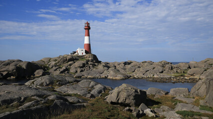 Red and white cast iron Eigerøy Lighthouse and anorthosite rock formations, Norway.