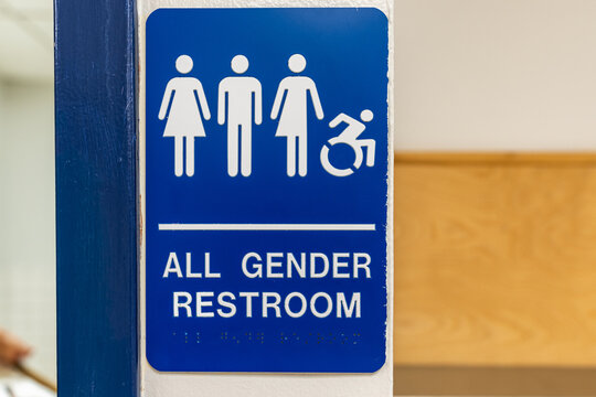 Blue and white all gender and accessible restroom sign with Braille code on an interior building wall..	