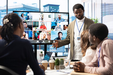 Company employees attending a meeting via videocall with investors, discussing about the future of the enterprise. Advisory board and workers examining infographics data for management.