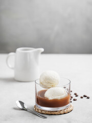 Affogato coffee with vanilla ice cream scoops and  espresso in a glass on a light  background with coffee beans and spoon.