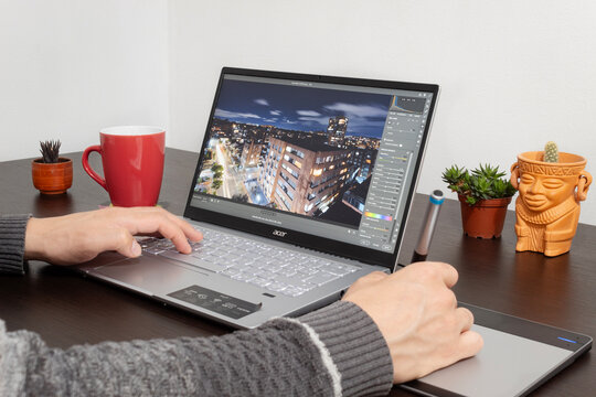 Close up to a photographer working on adobe Camera Raw software into a modern acer laptop