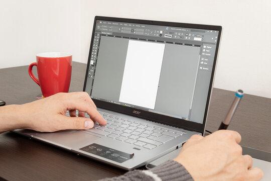 Graphic designer working with a wacom on adobe In Design software into a modern laptop 