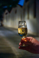 Hand with sherry wine glass with fino and old bogedas jerez wine cellars on background in Jerez de la Frontera, wine glasses outdoor, cityview, Andalusia, Spain