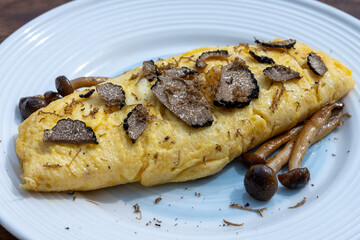 French omelette with mushrooms, fresh farmers eggs and black summer truffle mushroom in pieces for making truffle dishes with tasty aroma