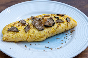 French omelette with mushrooms, fresh farmers eggs and black summer truffle mushroom in pieces for making truffle dishes with tasty aroma