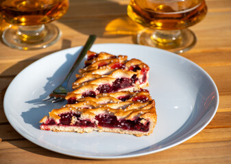Homemade open sour cherry pie, delicious sweet dessert served in pieces outdoor in garden